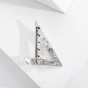 Spilla creativa a forma di squadra in argento con strass incastonati e perla pendente