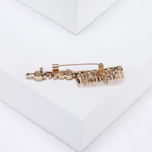 Détail de la broche peigne dorée créative avec strass étincelants et finition en alliage