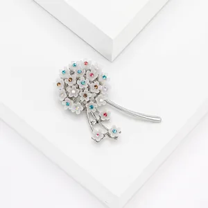Silver dandelion bouquet brooch with colorful rhinestones on a white geometric backdrop