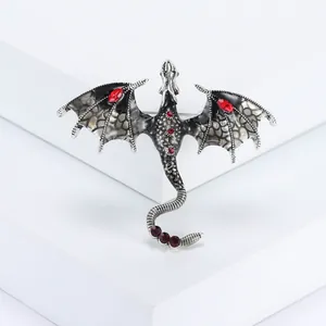 Macro detail of silver dragon brooch with black enamel wings and red crystals