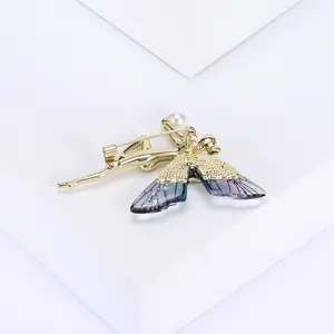 Détail d'une broche fée papillon avec ailes dégradées violettes et perle élégante