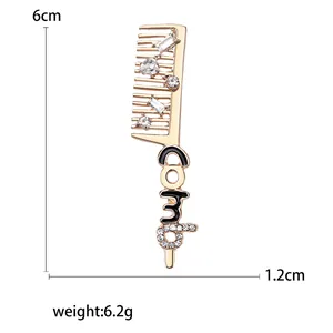 Broche en forme de peigne doré avec strass brillants et gravure de texte COMB