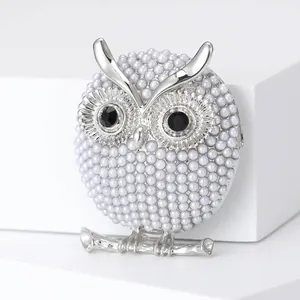Broche chouette élégante avec perles blanches et yeux en pierres noires sur base argentée