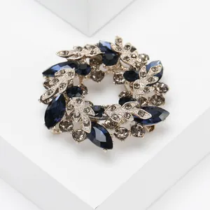 Détail d'une broche couronne argentée avec pierres bleues et motifs de feuilles