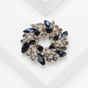 Gros plan sur l'élégante broche couronne florale avec strass bleu foncé et alliage argenté