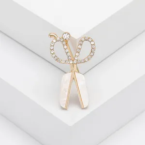 Elegante broche de tijera con diamantes de imitación y nácar sobre soporte blanco