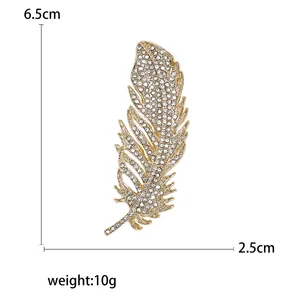 Elegante spilla a piuma dorata con strass bianchi, misura 6,5 cm per 2,5 cm
