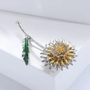 Gros plan d'une broche pissenlit avec pétales dorés et détails de feuilles vertes