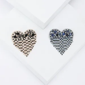 Spilla elegante a cuore con nappe e strass su espositore geometrico bianco moderno