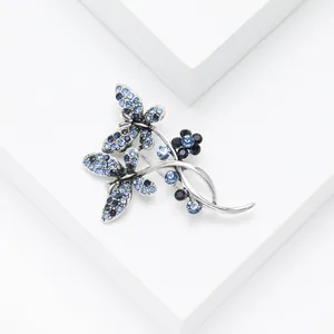 Exquisite blue rhinestone butterfly and flower brooch pin on a minimalist white pedestal
