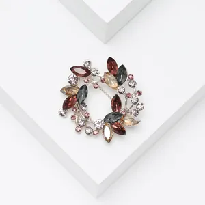 Detail of a crystal olive wreath brooch with multi-colored stones on a silver base