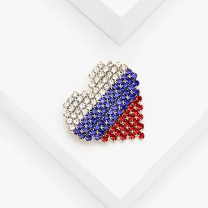 Macro detail of a heart-shaped brooch with blue, white, and red rhinestones on gold base