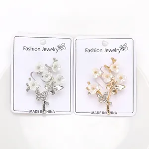 Détail de broches fleur et papillon en argent et or avec strass sur carte de support
