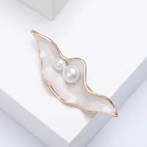 Macro detail of leaf-shaped enamel brooch with pearls and pink marble texture