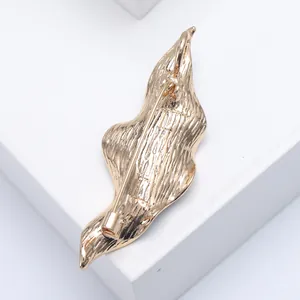 Detailed back view of gold enamel leaf brooch showing metal texture and safety pin buckle