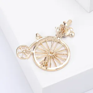 Dettaglio macro di una spilla a forma di bici d'epoca con finitura in oro lucido e spilla