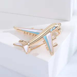 Detailed macro view of airplane brooch featuring gold plating and light blue enamel work