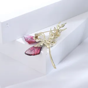 Makroaufnahme einer Schmetterlingsbrosche in Gold mit rosa Farbverlauf und Nadel