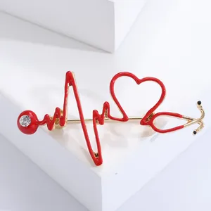 Détail du design de broche stéthoscope avec émail rouge et finitions en métal doré
