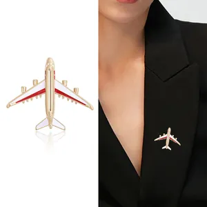 Fashionable gold airplane brooch with red and white enamel details on a suit lapel