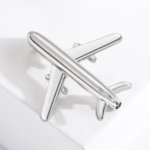 Minimalist silver airplane brooch with a polished metallic finish on marble base
