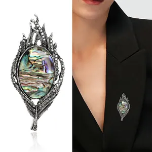 Vintage abalone shell feather brooch with silver metal and crystals on a black blazer