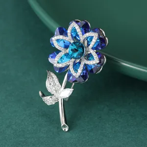 Exquisite crystal flower brooch with blue stones and silver plating on dark green texture