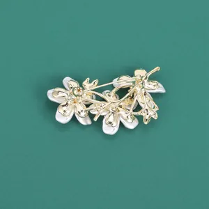 Detail view of the golden metal base and secure pin clasp on the peach blossom brooch