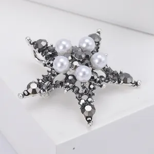 Macro shot of silver star brooch featuring white pearls and dark crystal rhinestones