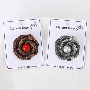 Close-up of vintage rose brooches with sparkling rhinestones and center pearls on display card