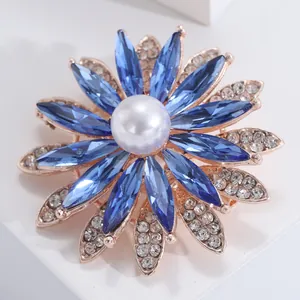Broche tournesol avec pierres bleues, perle centrale et finition or rose