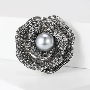 Vintage gunmetal rose brooch with black rhinestones and a grey pearl center on white stairs