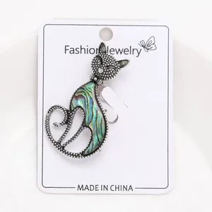 Macro view of vintage cat brooch featuring iridescent abalone shell inlay on white card