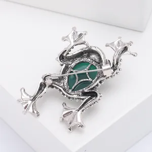 Detail of vintage silver frog brooch back with green gemstone and secure pin clasp