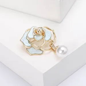 Nahaufnahme der goldenen Kamelienbrosche mit blauen Emaille-Blüten und weißer Perle