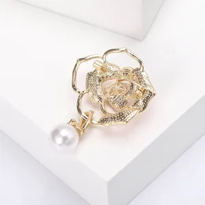 Detailansicht der goldenen Blumenbrosche mit Perlenanhänger und Sicherheitsnadelverschluss