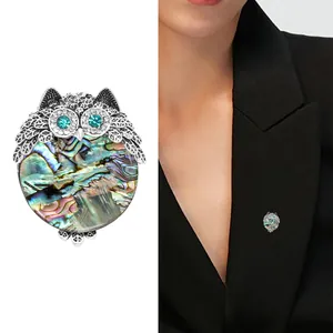 Retro owl brooch with colorful abalone shell and crystal eyes on a black blazer