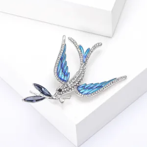 Detailed close-up of a swallow brooch with blue enamel wings and sparkling rhinestones