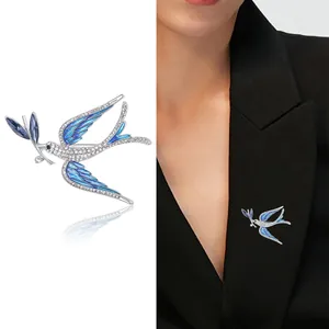 Exquisite swallow brooch with blue enamel and rhinestones shown on a black suit blazer