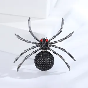 Vintage Spinnenbrosche mit schwarzen Strasssteinen und roten Augen auf weißem Sockel