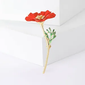 Broche fleur rouge élégante avec étamines dorées et feuilles vertes sur blocs blancs