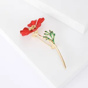 Détail d'une broche fleur coquelicot rouge avec étamines dorées sur marches blanches