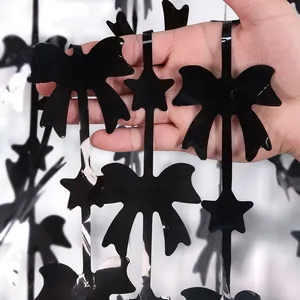 Macro detail of glossy black bow and star foil fringe curtain for party backdrops