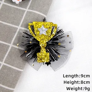 Dettaglio fermaglio per capelli a trofeo dorato con tulle nero e paillettes a stella