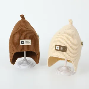 Close-up of brown and beige knitted baby earflap hats with pointed tops and patches