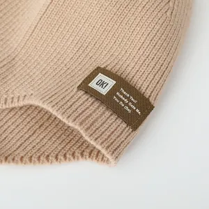 Detail of knit beanie showing ribbed texture and square fabric patch with letters