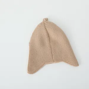 Close-up of beige ribbed knit baby beanie with ear flaps and woven side label