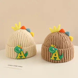 Close-up of knit winter hats with cartoon dinosaur fins and soft crown details for babies