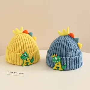 Detail of yellow and blue knitted beanies with cute dinosaur patches and 3D crown accents