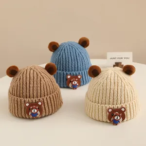 Dettaglio di berretti in maglia per neonati con orecchie da orso 3D marroni, blu e beige